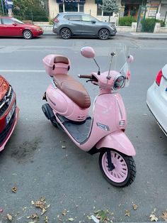 a pink scooter parked next to a red car