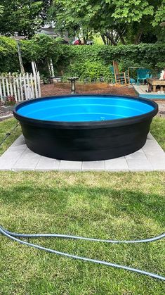 an above ground swimming pool in the middle of a yard with a hose attached to it