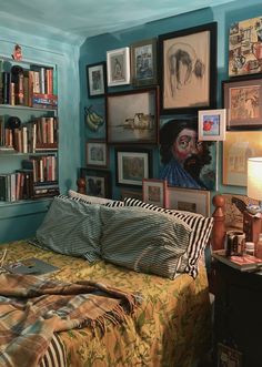 a bed in a room with many pictures on the wall and a lamp next to it