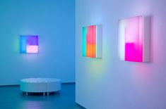 three colorful paintings on the wall next to each other in a room with blue walls