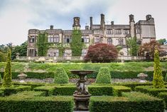 a large building with hedges surrounding it and a fountain in the center surrounded by bushes