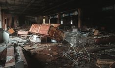 an abandoned shopping cart sitting in the middle of a room filled with debris and broken furniture