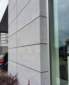 the side of a building with cars parked in front of it and another car behind it