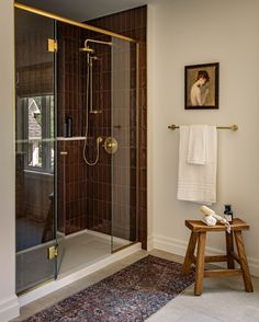 a walk in shower sitting next to a wooden stool