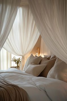 a bed with white drapes and pillows on it