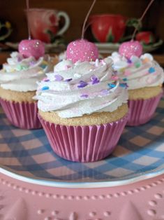 three cupcakes with white frosting and sprinkles on a plate