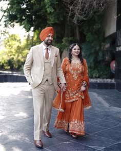 a man and woman dressed in orange walking together