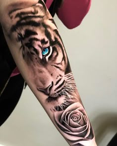 a tiger with blue eyes and a rose tattoo on the left inner arm is shown