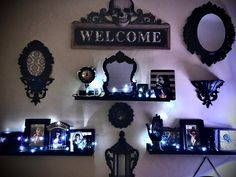 there are many pictures on the wall with lights around them and some mirrors above it