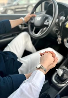 two people holding hands while sitting in a car