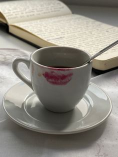 a cup and saucer on a table with an open book
