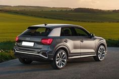 an audi suv is parked on the side of the road in front of a field