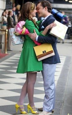 a man in a suit and tie hugging a woman with shopping bags on the street