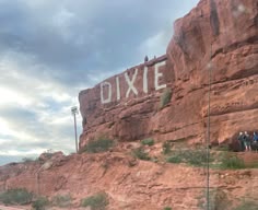 some people are standing on the side of a road next to a large rock formation