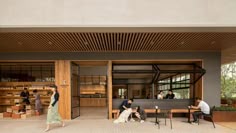 people sitting at tables in front of a building with wooden slats on the roof