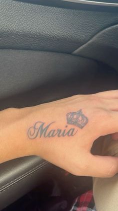 a woman's hand with a crown tattoo on her left wrist and the word marina written in cursive font