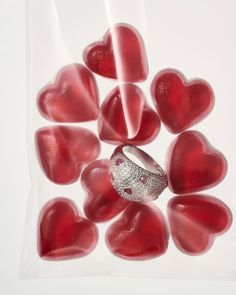 a wedding ring surrounded by red hearts