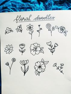 a piece of paper with flowers drawn on it and the words floral doodles written in black ink