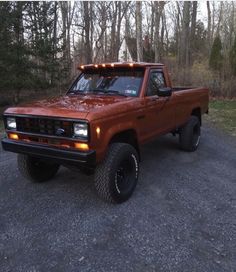 an orange pick up truck with lights on it's hood parked in the woods
