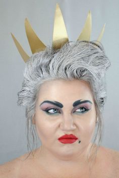 a woman with grey hair and makeup wearing a crown on top of her head is looking at the camera