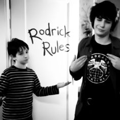 two young men standing next to each other in front of a whiteboard with writing on it