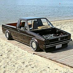 an old pickup truck is parked on the beach by the water with its hood open