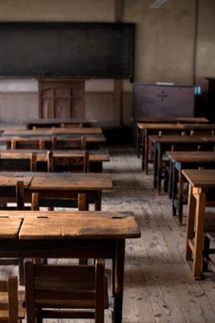 an empty classroom with wooden desks and chairs