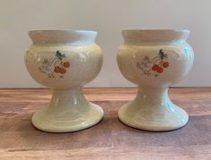 two white vases sitting on top of a wooden table