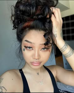 a young woman with tattoos on her face and arm, wearing a black bra top