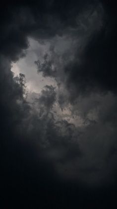 an airplane is flying in the dark cloudy sky