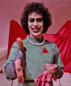 a man dressed in costume giving the thumbs up while holding a drink and wearing gloves