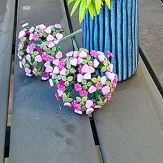 a blue vase with flowers and an umbrella sitting on a bench next to a flower pot