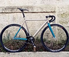 a silver and blue bike parked on the side of a road next to a wall