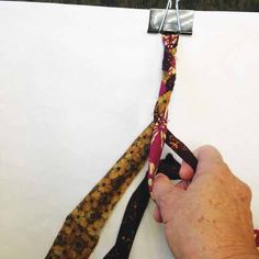 a hand holding a tie on top of a piece of paper next to a pair of scissors