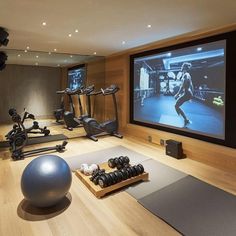 a home gym with exercise equipment and a large screen tv on the wall behind it