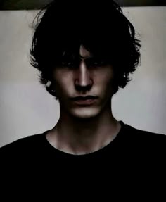 a man with dark hair and black shirt looking at the camera