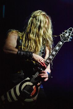 a man with long hair playing an electric guitar