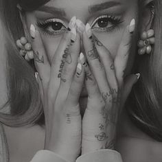 a woman with tattoos covering her face and hands over her eyes while holding her hands to her face