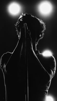 a black and white photo of a woman with her hands on her hips in front of spotlights