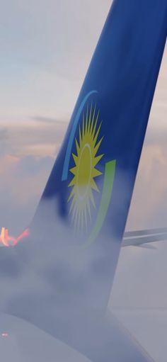 the tail end of an airplane as it flies in the sky with clouds around it