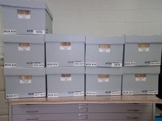 several boxes are stacked on top of each other in an office area with drawers and file cabinets