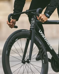 a close up of a person riding a bike on the street with their hand on the wheel