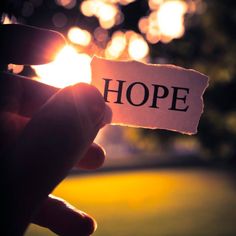 someone holding up a piece of paper with the word hope on it