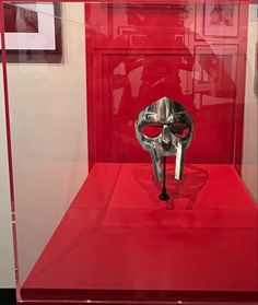 a red display case with a silver mask in it