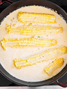 cooked corn on the cob being sauteed in a skillet with white sauce