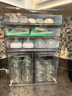 an assortment of jars and containers are stacked on top of each other in a glass case