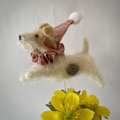 there is a stuffed dog with a hat on its head and flowers in the vase