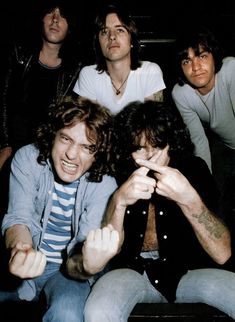 a group of men sitting next to each other in front of a sign that says ac dc