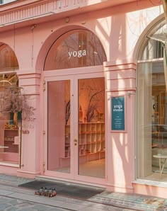 a pink store front with the words yoga on it's glass doors and windows