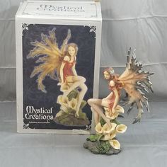 a figurine of a fairy sitting next to a box with the word musical creations on it